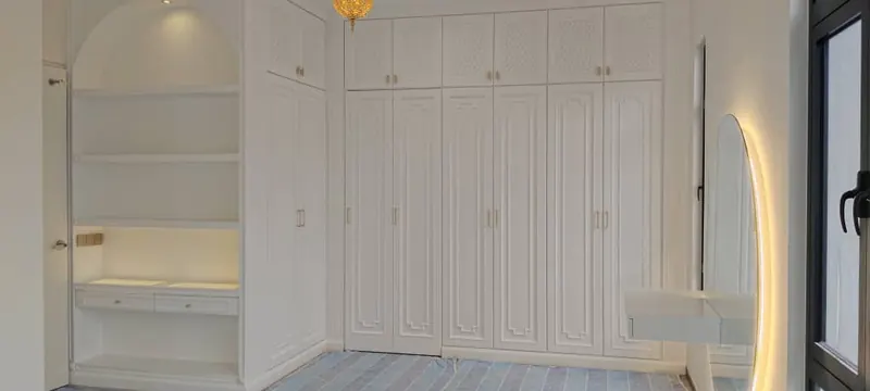 Completed white bedroom wardrobe with arched display shelf and dressing table
