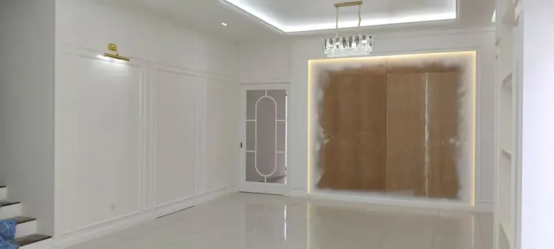 Completed living hall with white panelling, chandelier and a lit timber feature wall