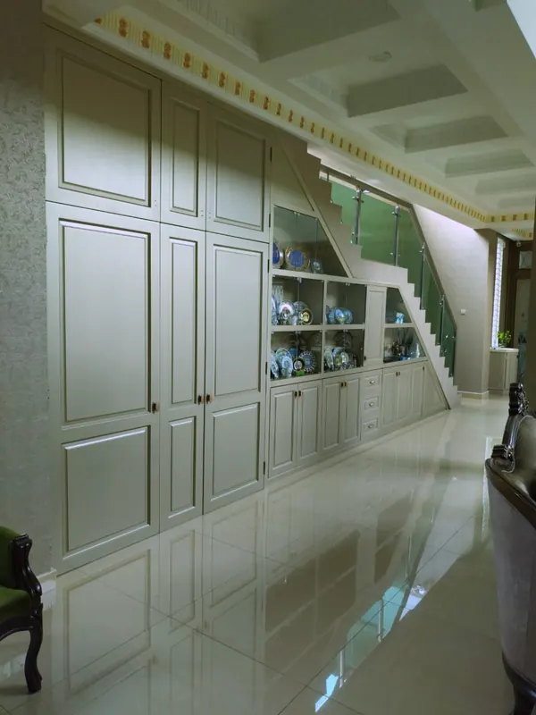 Completed panelled cabinets and display shelving built under a staircase